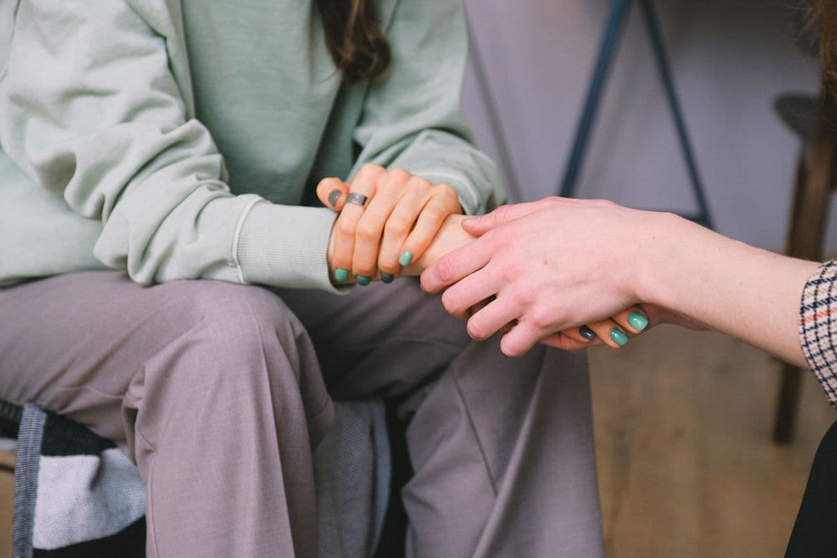 One seated person holding another person’s hand